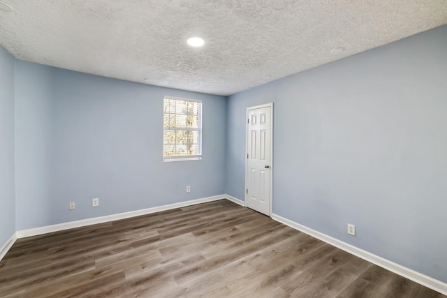 spare room featuring hardwood / wood-style floors and a textured ceiling