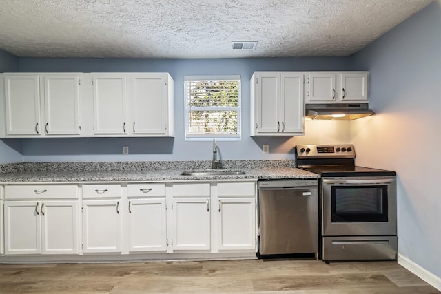 kitchen featuring appliances with stainless steel finishes, white cabinetry, sink, light stone counters, and light hardwood / wood-style flooring