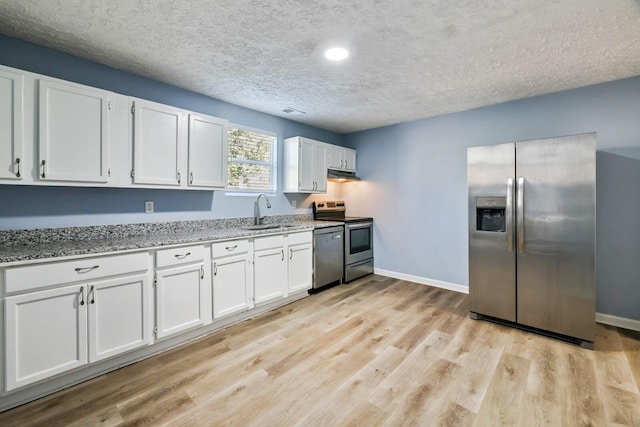 kitchen featuring stainless steel appliances, light stone countertops, white cabinets, and a textured ceiling