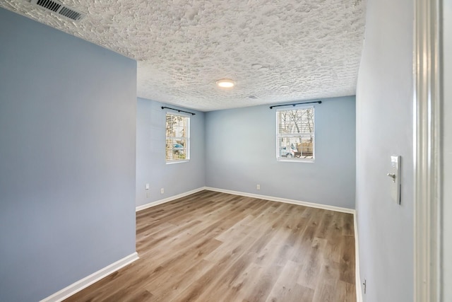 empty room featuring a textured ceiling and light wood-type flooring