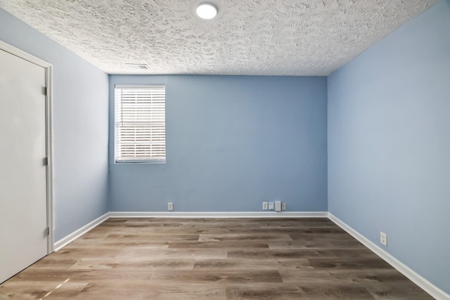 empty room featuring wood-type flooring and a textured ceiling