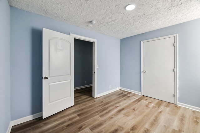 unfurnished bedroom with a closet, wood-type flooring, and a textured ceiling