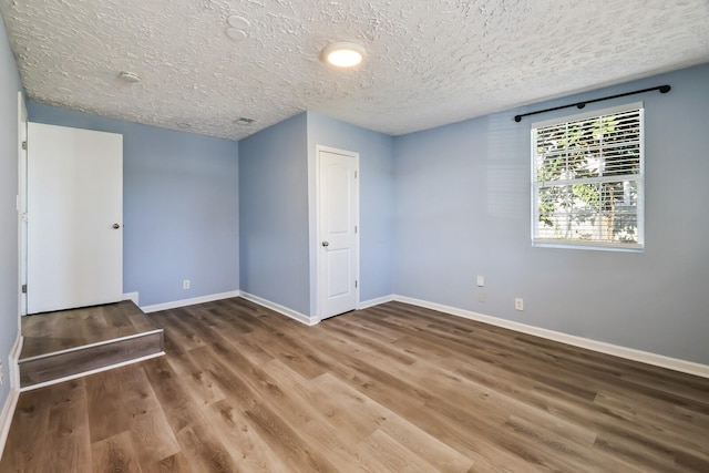 spare room with dark wood-type flooring and a textured ceiling