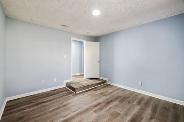 spare room with hardwood / wood-style floors and a textured ceiling