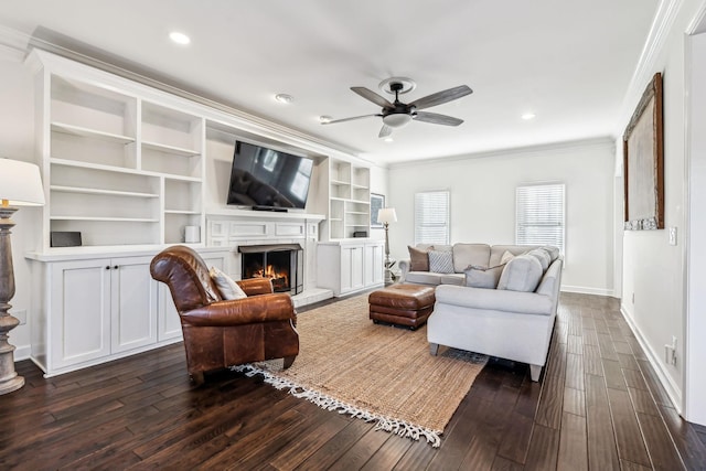 living room with dark wood-type flooring, ceiling fan, ornamental molding, and built in features