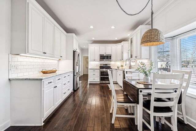 kitchen with appliances with stainless steel finishes, pendant lighting, and white cabinets