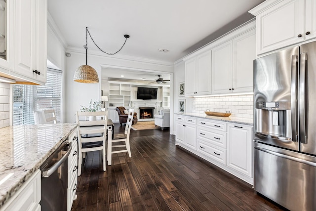 kitchen with hanging light fixtures, backsplash, stainless steel appliances, light stone countertops, and white cabinets