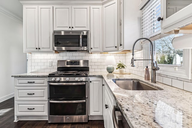 kitchen featuring white cabinetry, sink, light stone counters, stainless steel appliances, and crown molding