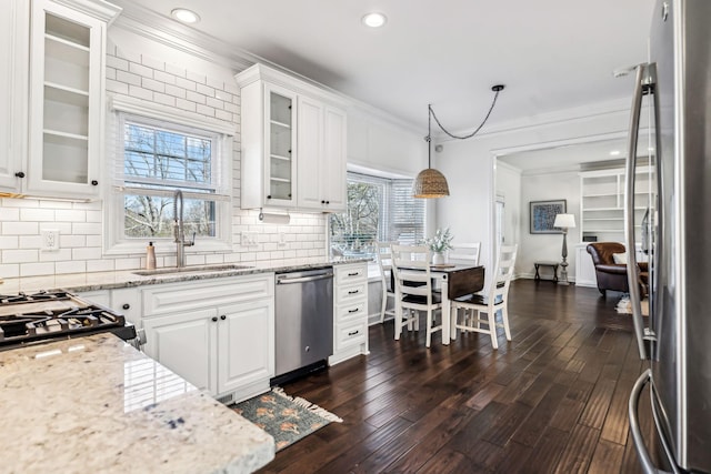 kitchen with sink, hanging light fixtures, stainless steel appliances, light stone counters, and white cabinets