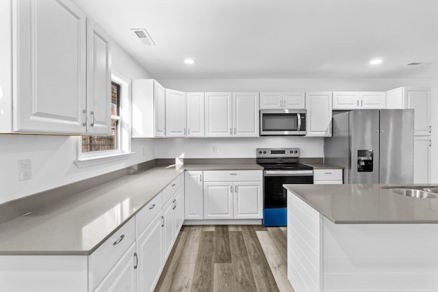 kitchen featuring stainless steel appliances, white cabinets, and light wood-type flooring