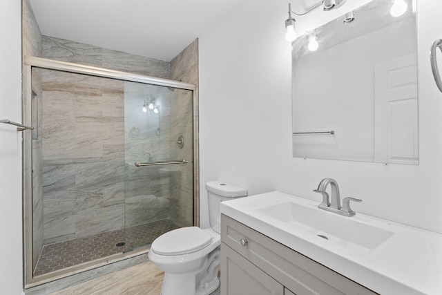 bathroom featuring vanity, toilet, and a shower with door