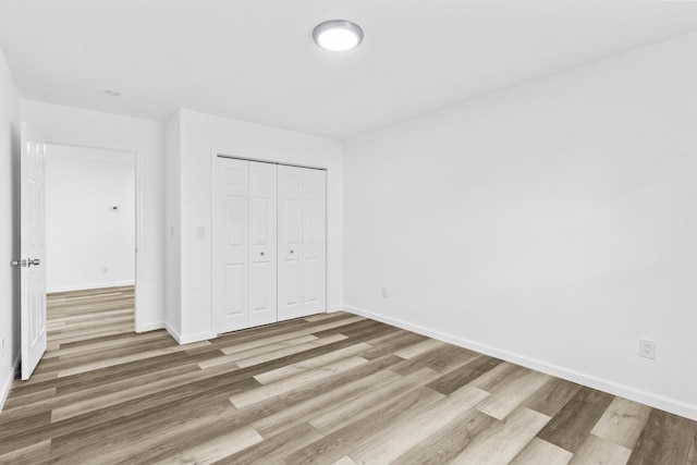 unfurnished bedroom featuring wood-type flooring and a closet