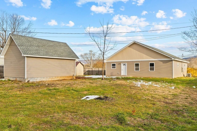 rear view of house featuring cooling unit and a lawn