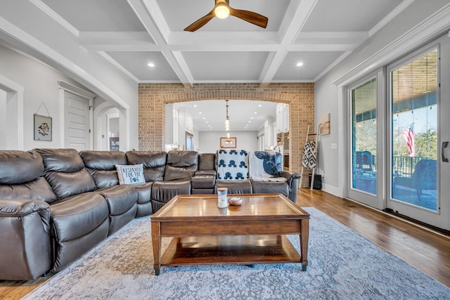 living room with coffered ceiling, hardwood / wood-style flooring, ornamental molding, beamed ceiling, and brick wall