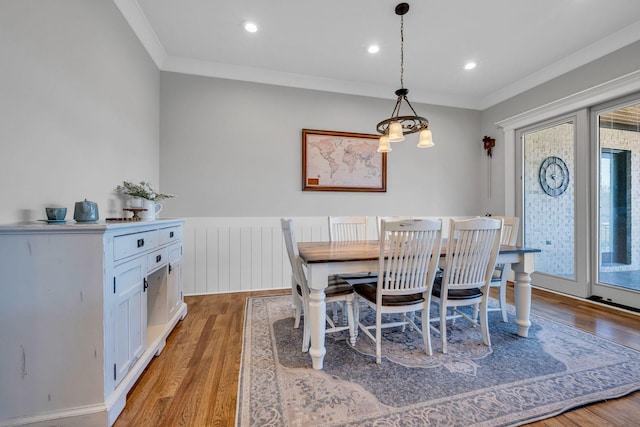 dining area with ornamental molding and light hardwood / wood-style flooring