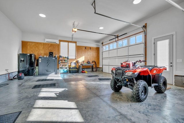 garage featuring black fridge, a wall mounted air conditioner, a garage door opener, and wood walls