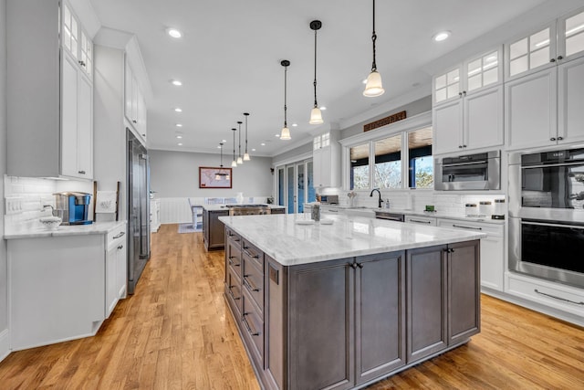 kitchen with hanging light fixtures, a center island, white cabinets, and stainless steel appliances