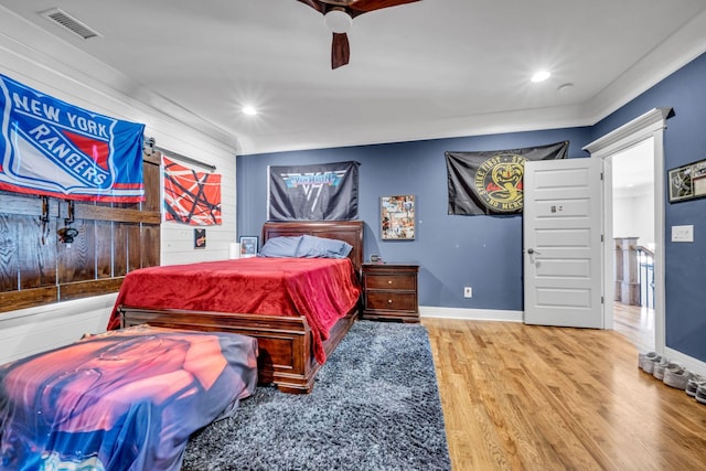 bedroom with hardwood / wood-style floors, ornamental molding, and ceiling fan