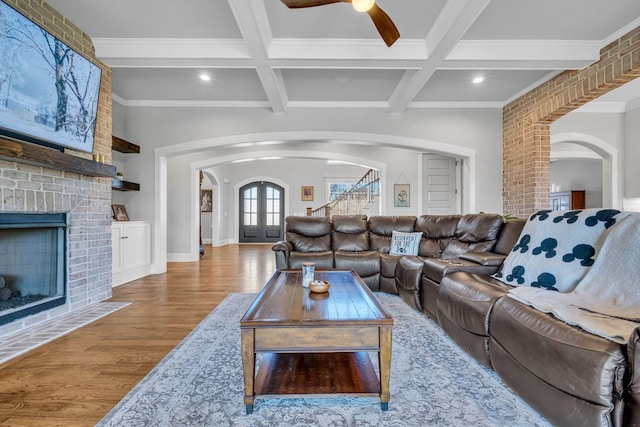 living room featuring hardwood / wood-style floors, beamed ceiling, ornamental molding, coffered ceiling, and french doors