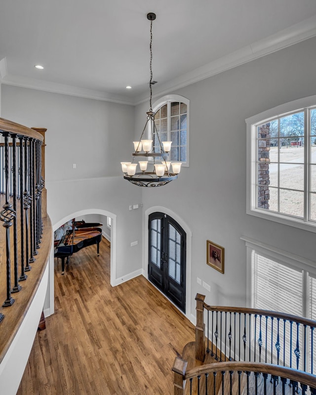 foyer entrance with an inviting chandelier, hardwood / wood-style floors, ornamental molding, and french doors