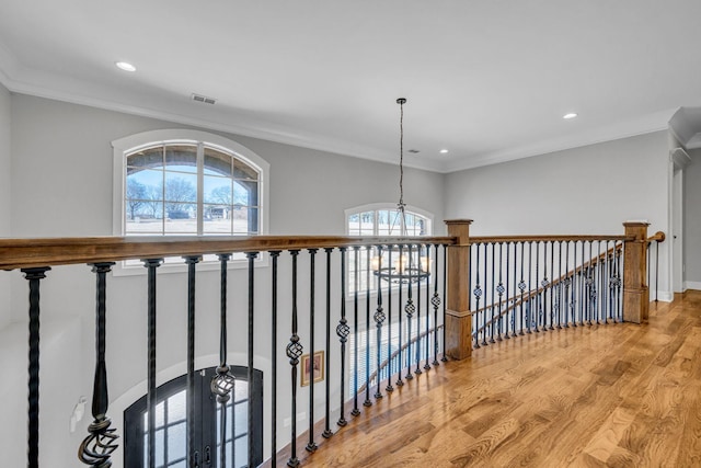 hallway with a notable chandelier, crown molding, and light wood-type flooring