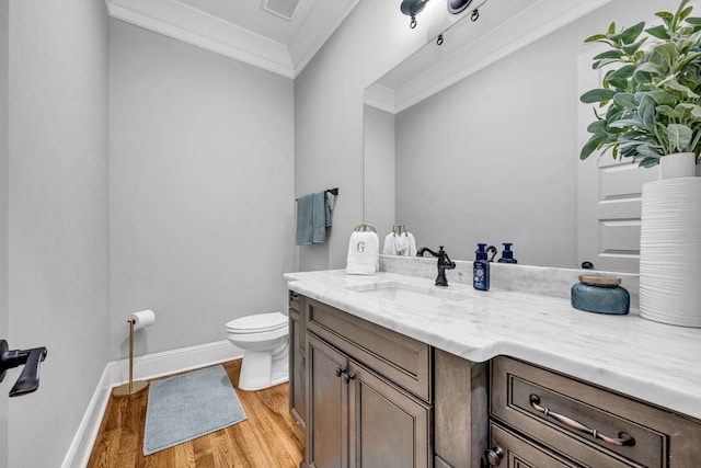 bathroom featuring hardwood / wood-style flooring, vanity, crown molding, and toilet