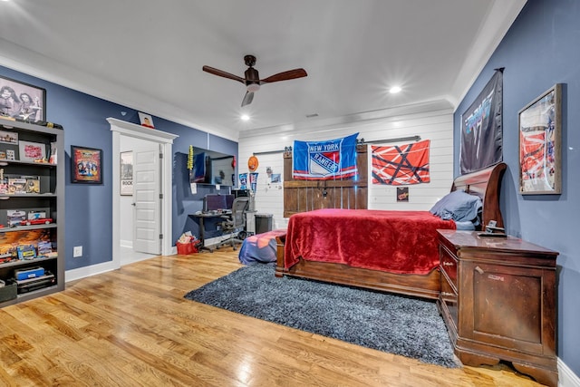 bedroom featuring hardwood / wood-style flooring, ceiling fan, ornamental molding, and wooden walls