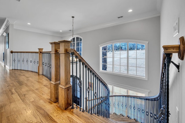 stairway with hardwood / wood-style floors, crown molding, and a chandelier