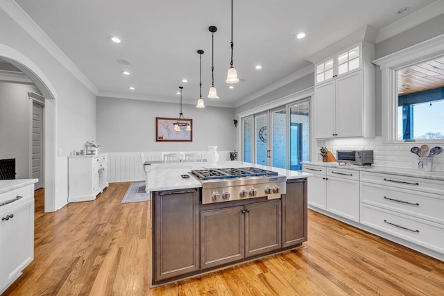 kitchen featuring pendant lighting, light hardwood / wood-style flooring, a center island, white cabinets, and stainless steel gas stovetop