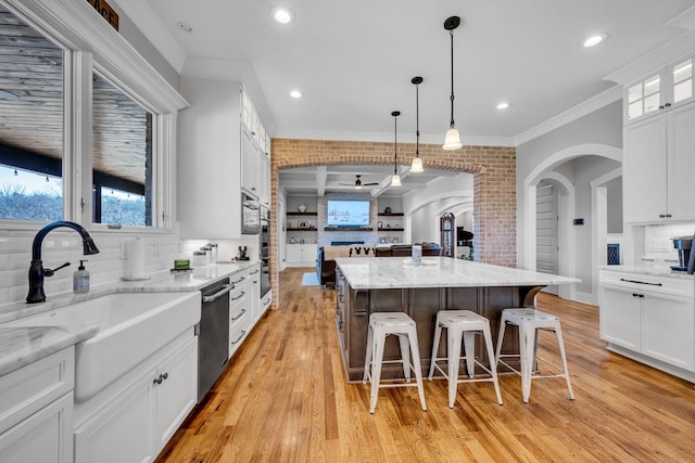 kitchen featuring sink, a center island, a kitchen breakfast bar, pendant lighting, and white cabinets