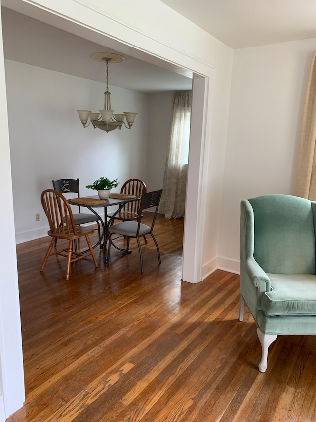 dining room with dark wood-type flooring and an inviting chandelier