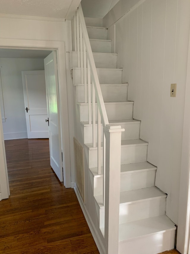 stairway with wood-type flooring and ornamental molding