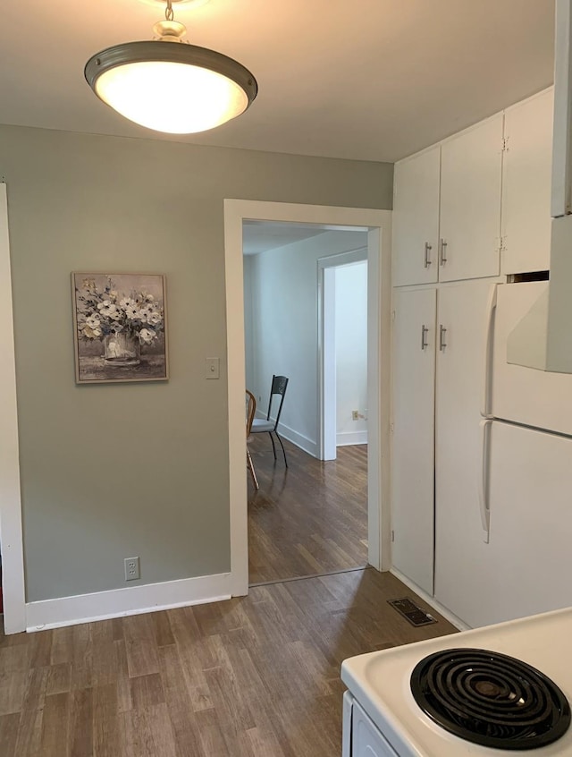 kitchen with electric stove, dark hardwood / wood-style floors, white fridge, and white cabinets