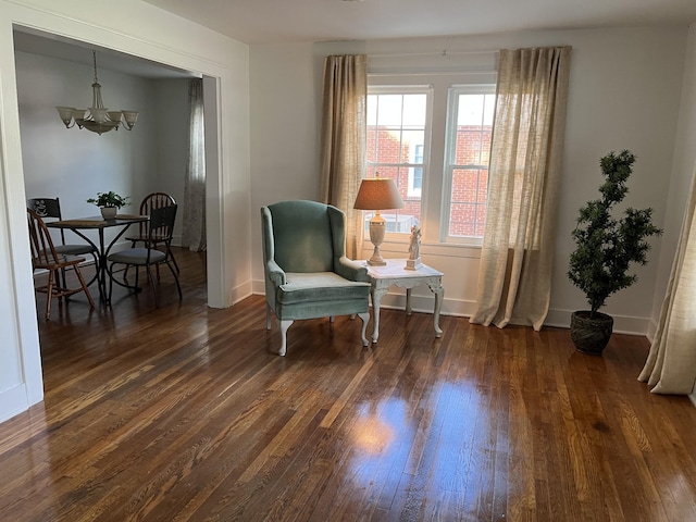 sitting room with a notable chandelier and dark wood-type flooring