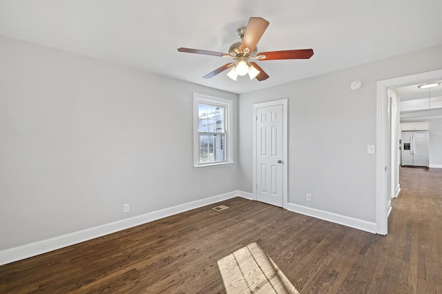 unfurnished bedroom with a closet, dark wood-type flooring, ceiling fan, and stainless steel fridge with ice dispenser