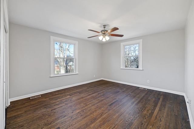 spare room featuring a wealth of natural light, dark wood-type flooring, and ceiling fan