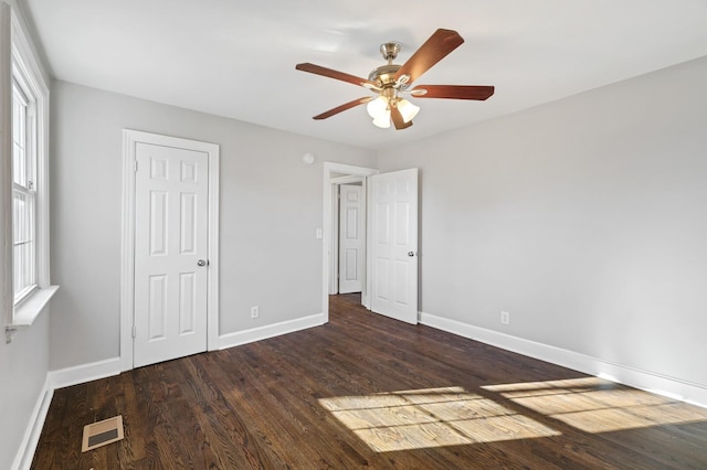 unfurnished bedroom with ceiling fan, dark hardwood / wood-style flooring, and a closet