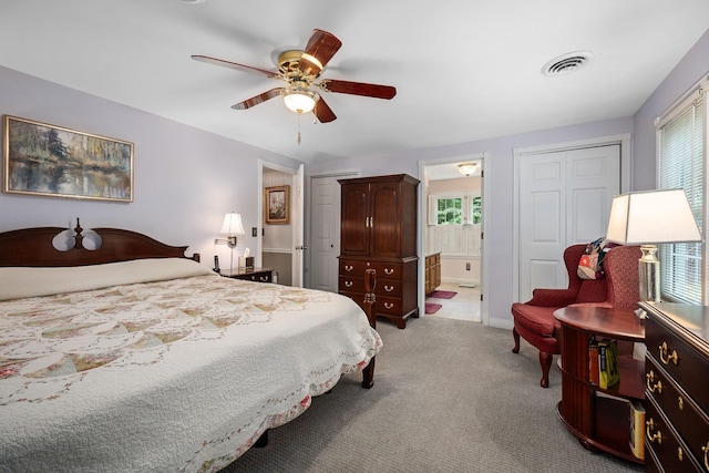 bedroom featuring light colored carpet, ceiling fan, and ensuite bathroom