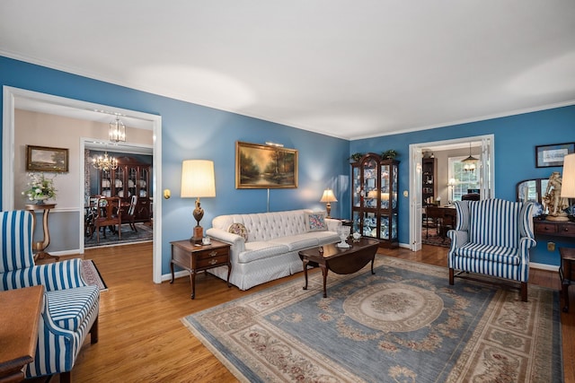 living room with crown molding, hardwood / wood-style floors, and a notable chandelier