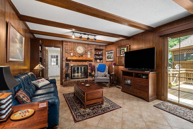 living room with beamed ceiling, a fireplace, wooden walls, and a textured ceiling