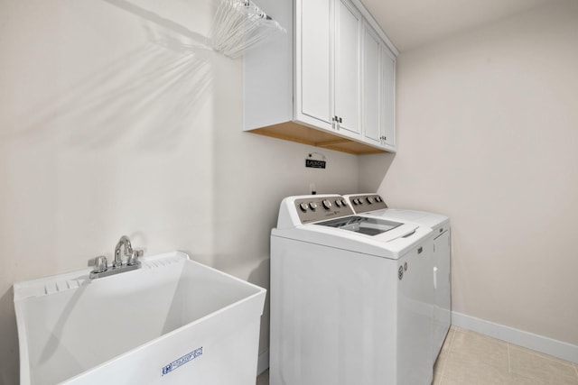 clothes washing area with cabinets, washing machine and clothes dryer, and sink