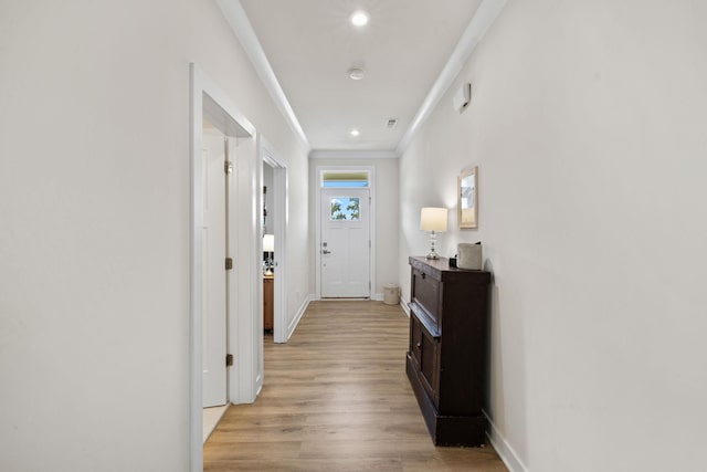 hallway with ornamental molding and light hardwood / wood-style floors