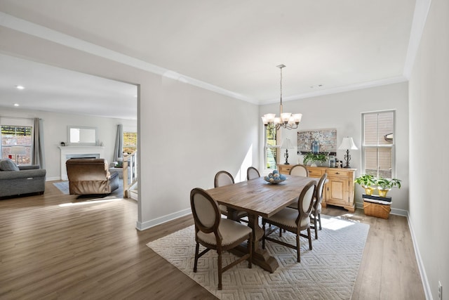 dining space with crown molding, plenty of natural light, an inviting chandelier, and light wood-type flooring