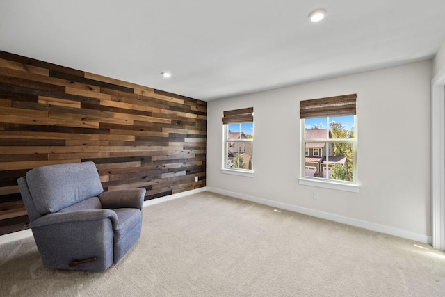 sitting room featuring light carpet and wood walls