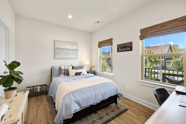 bedroom with hardwood / wood-style flooring and multiple windows