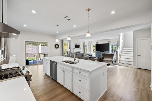 kitchen featuring sink, white cabinetry, hanging light fixtures, a center island with sink, and stainless steel dishwasher