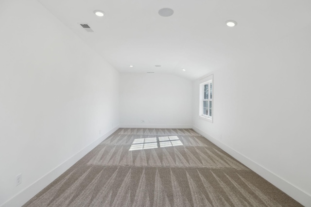 carpeted empty room featuring lofted ceiling