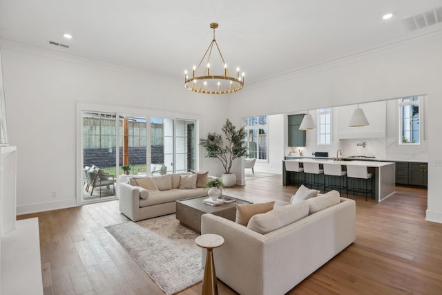 living room featuring ornamental molding, an inviting chandelier, and light hardwood / wood-style floors