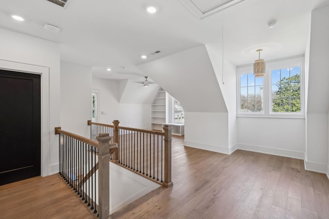 bonus room with built in shelves, ceiling fan, and hardwood / wood-style flooring