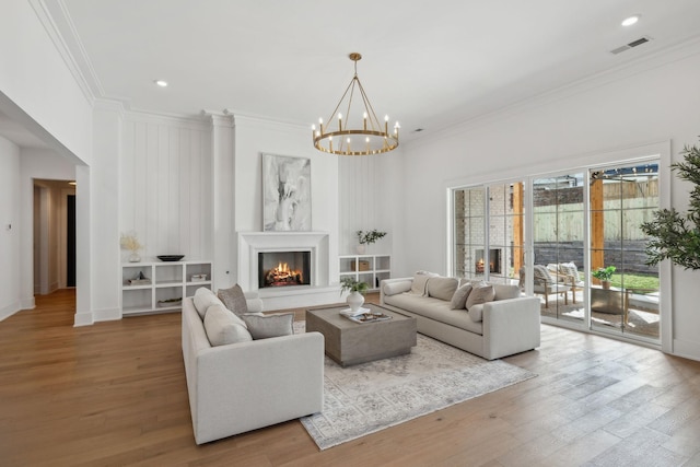 living room featuring ornamental molding, a notable chandelier, and light hardwood / wood-style flooring